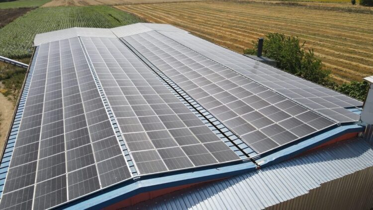 Solar panels on an industrial roof beside farmland